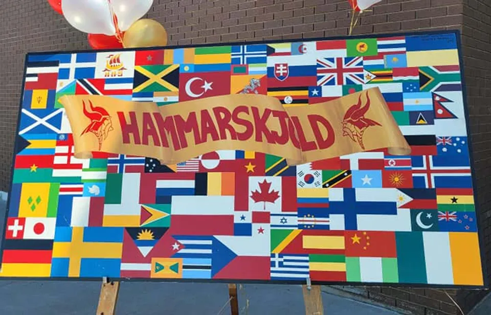 Un grande striscione con la scritta Hammarskjold High School circondato da un collage di diverse bandiere nazionali.