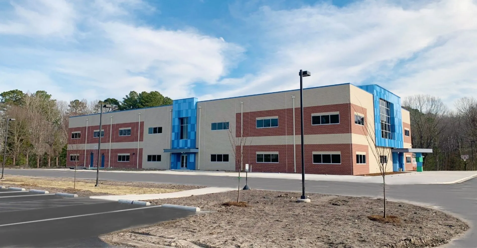 L'edificio moderno a più piani della Atlantic Shores Christian School è circondato da alberi e un cielo terso.