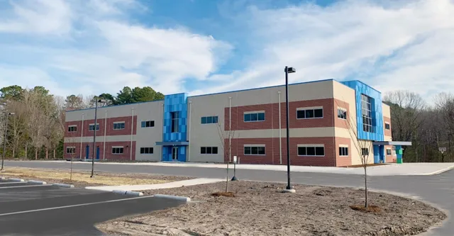 L'edificio moderno a più piani della Atlantic Shores Christian School è circondato da alberi e un cielo terso.