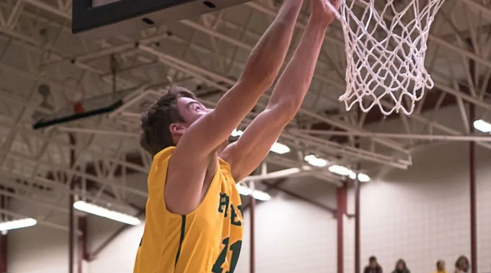 Uno studente del John Taylor Collegiate fa una schiacciata durante l'allenamento di basket in palestra.