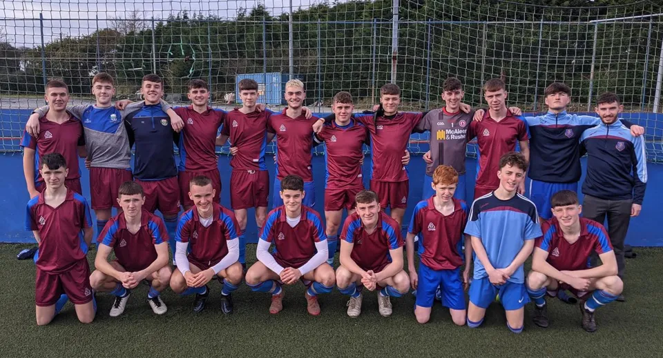 Un gruppo di calciatori posa sul campo da gioco della Scoil Mhuire gan Smál con maglie rosse e blu.