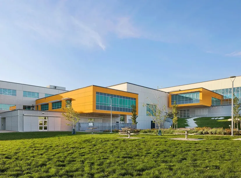 L'edificio moderno a più piani della Burnaby North School, con la sua facciata gialla, si trova su un prato ben curato circondato da una verde vegetazione.