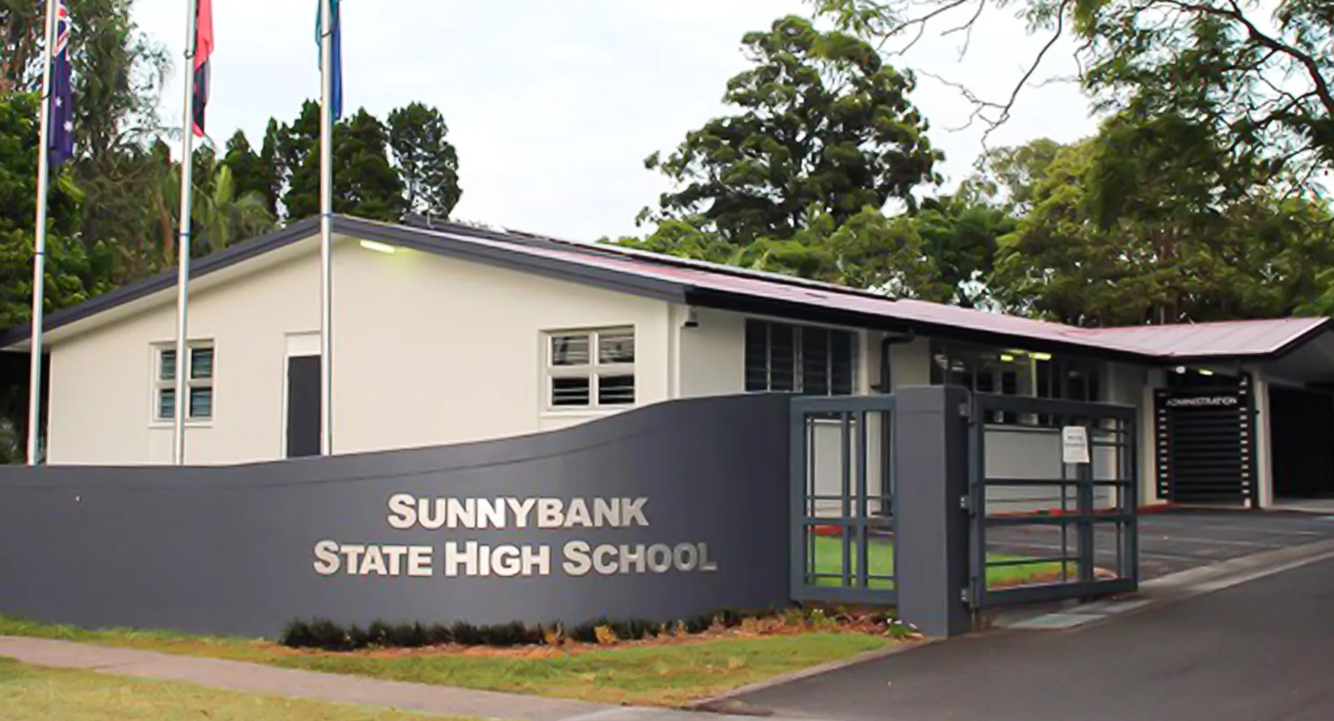 L'edificio scolastico moderno della Sunnybank State High School è circondato da alberi verdi.