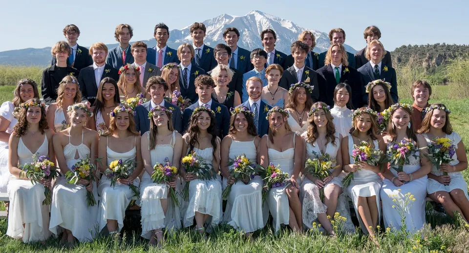 Un grande gruppo di studenti della Colorado Rocky Mountain School vestiti eleganti davanti a uno sfondo montano innevato.