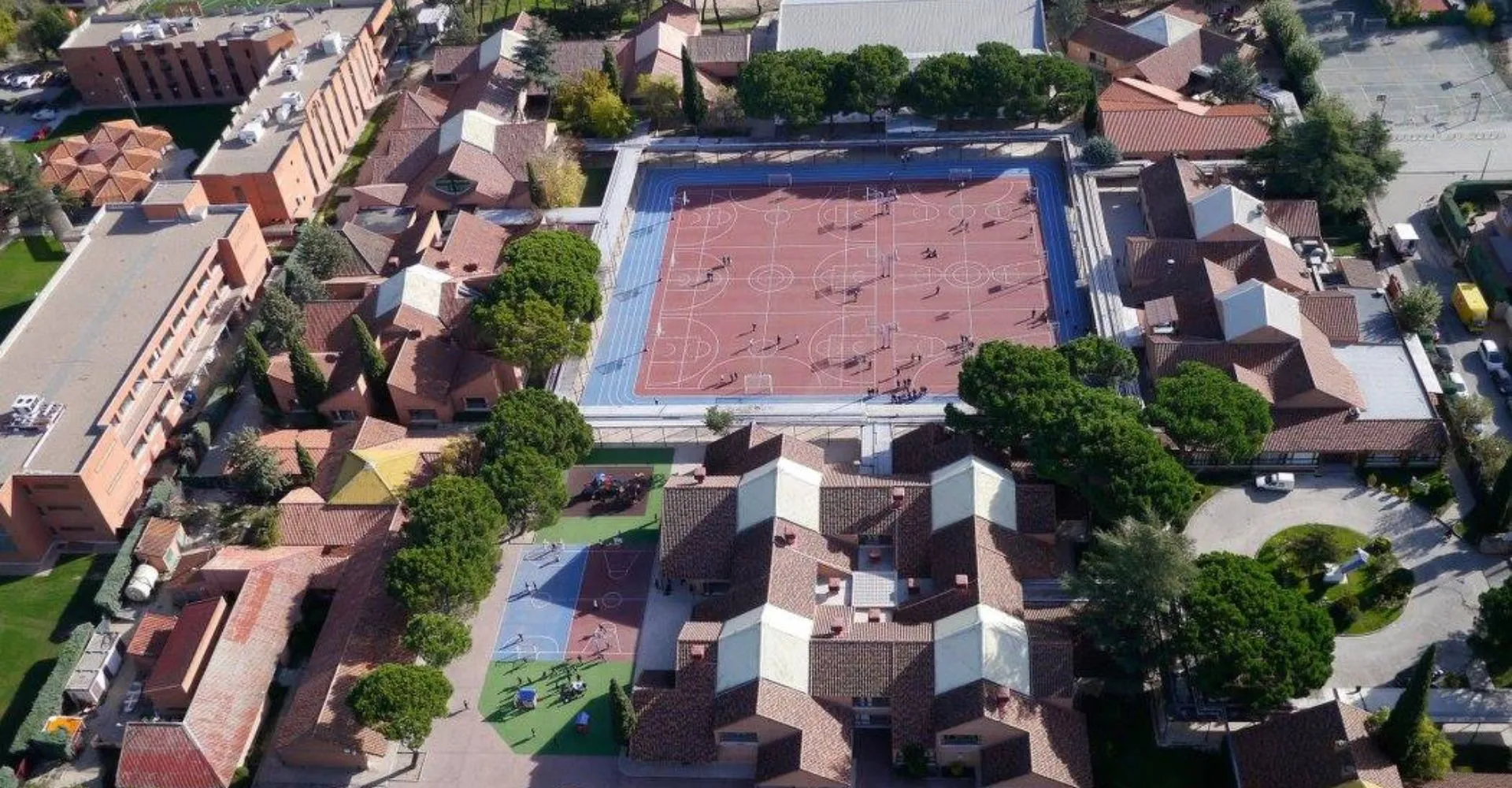 Vista aerea della SEK International School El Castillo con il grande edificio principale dal tetto rosso e le case residenziali circostanti.