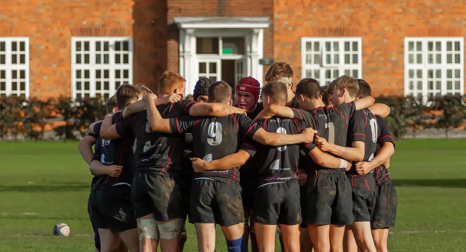 Un gruppo di studenti della Oakham School in divisa sportiva è davanti a un edificio in mattoni.