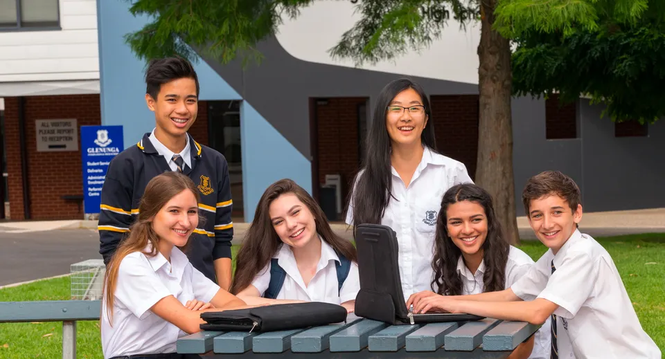 Un gruppo di studenti e studentesse si trova davanti all'edificio scolastico della Glenunga International High School, circondato da alberi e aree verdi.