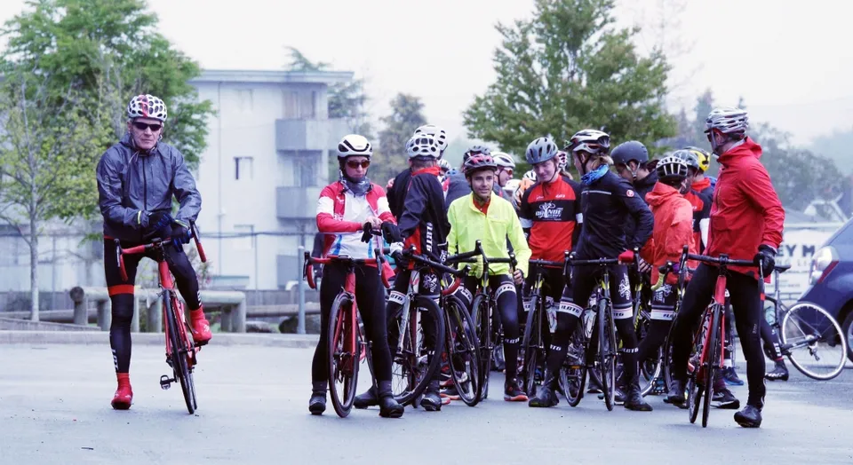 Un gruppo di studenti della École Entre-Lacs è in piedi in abbigliamento da ciclismo colorato davanti a un edificio scolastico.
