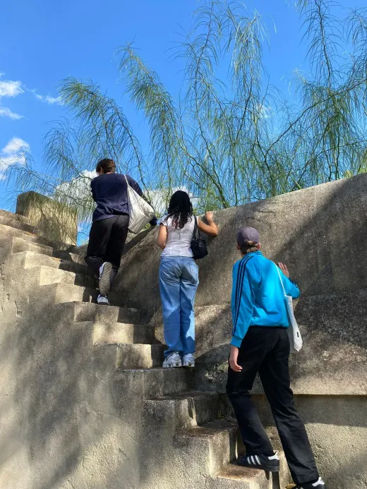 Tre studenti salgono una scalinata di pietra sotto un cielo azzurro
