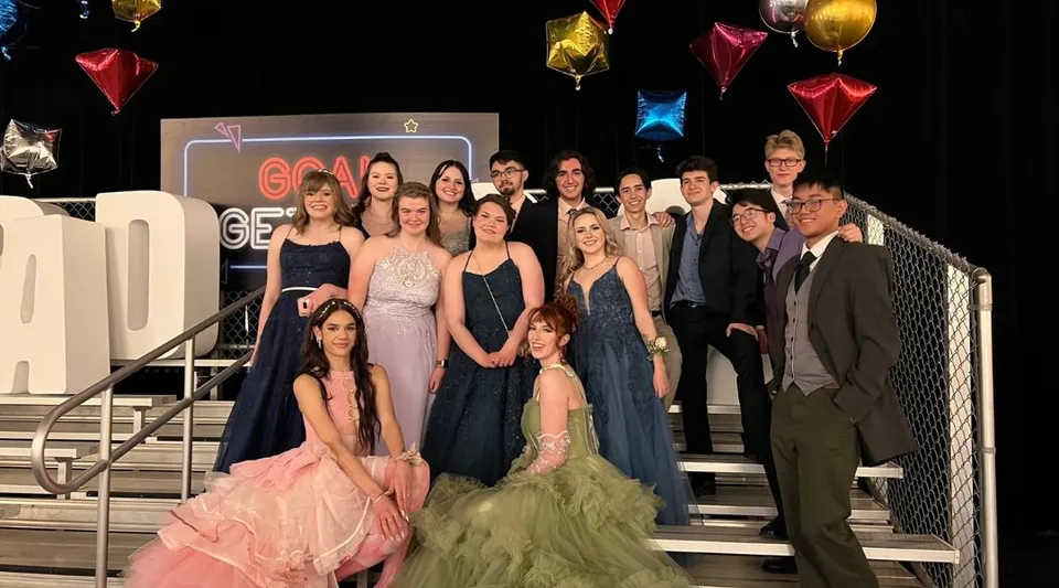 Un gruppo di studenti e studentesse della Bishop O'Byrne High School posa su un palco con palloncini colorati e decorazioni sullo sfondo.