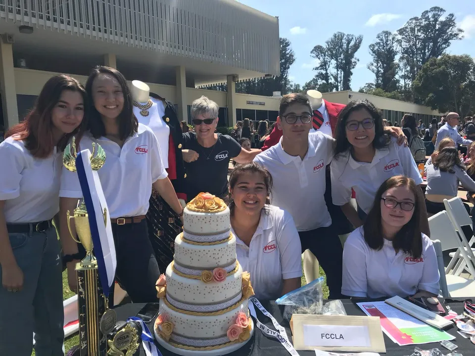 Studenti della San Luis Obispo High School festeggiano insieme all'aperto con una grande torta.