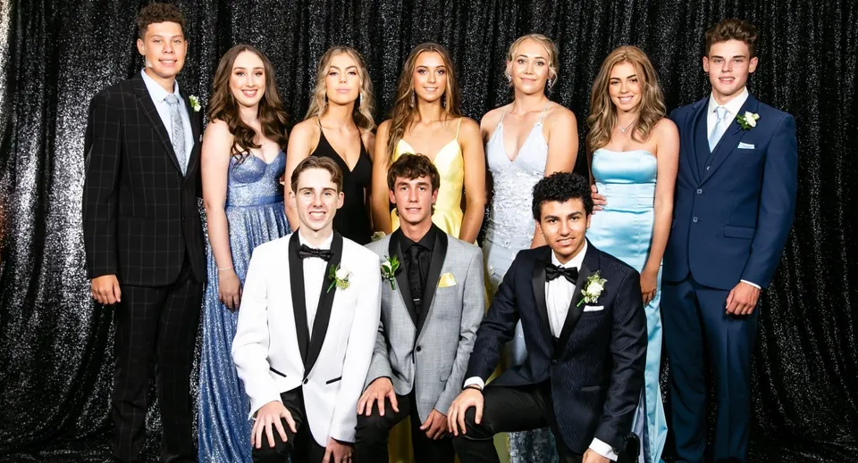 Un gruppo di persone posa a un evento formale davanti a uno sfondo nero presso la Cambridge High School.