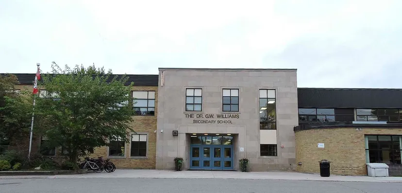 L'ingresso principale della Dr. G.W. Williams Secondary School con facciata in pietra e mattoni e porte blu.