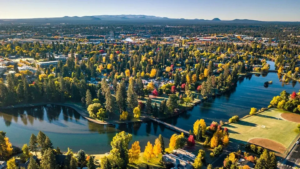 Vista aerea dei dintorni della Lindsay Thurber Comprehensive High School con alberi autunnali, un fiume e campi sportivi.