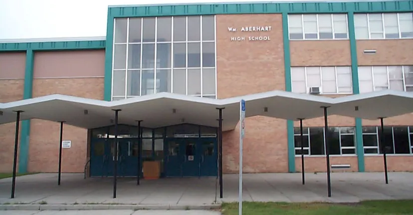L'edificio scolastico moderno a più piani della William Aberhart High School con vetrate e un'area verde circostante.