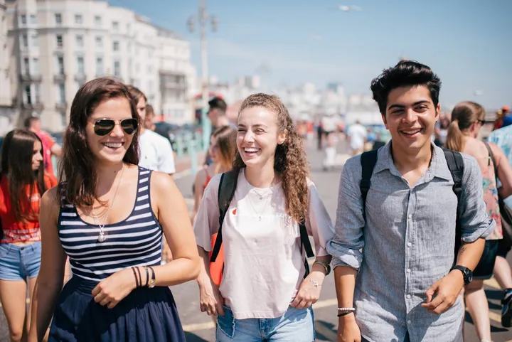 Drei Schüler der Sprachschule BLC lachen auf der Strandpromenade von Brighton