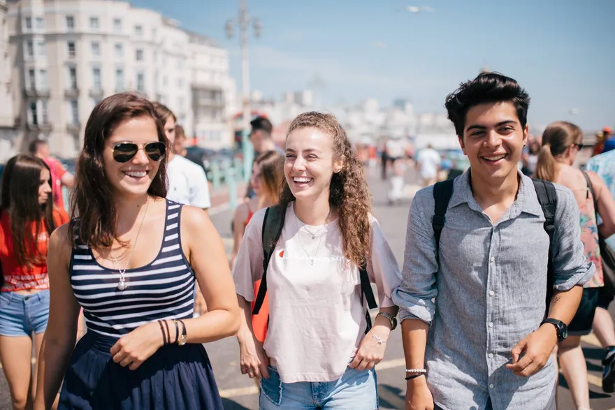 Drei Schüler der Sprachschule BLC lachen auf der Strandpromenade von Brighton