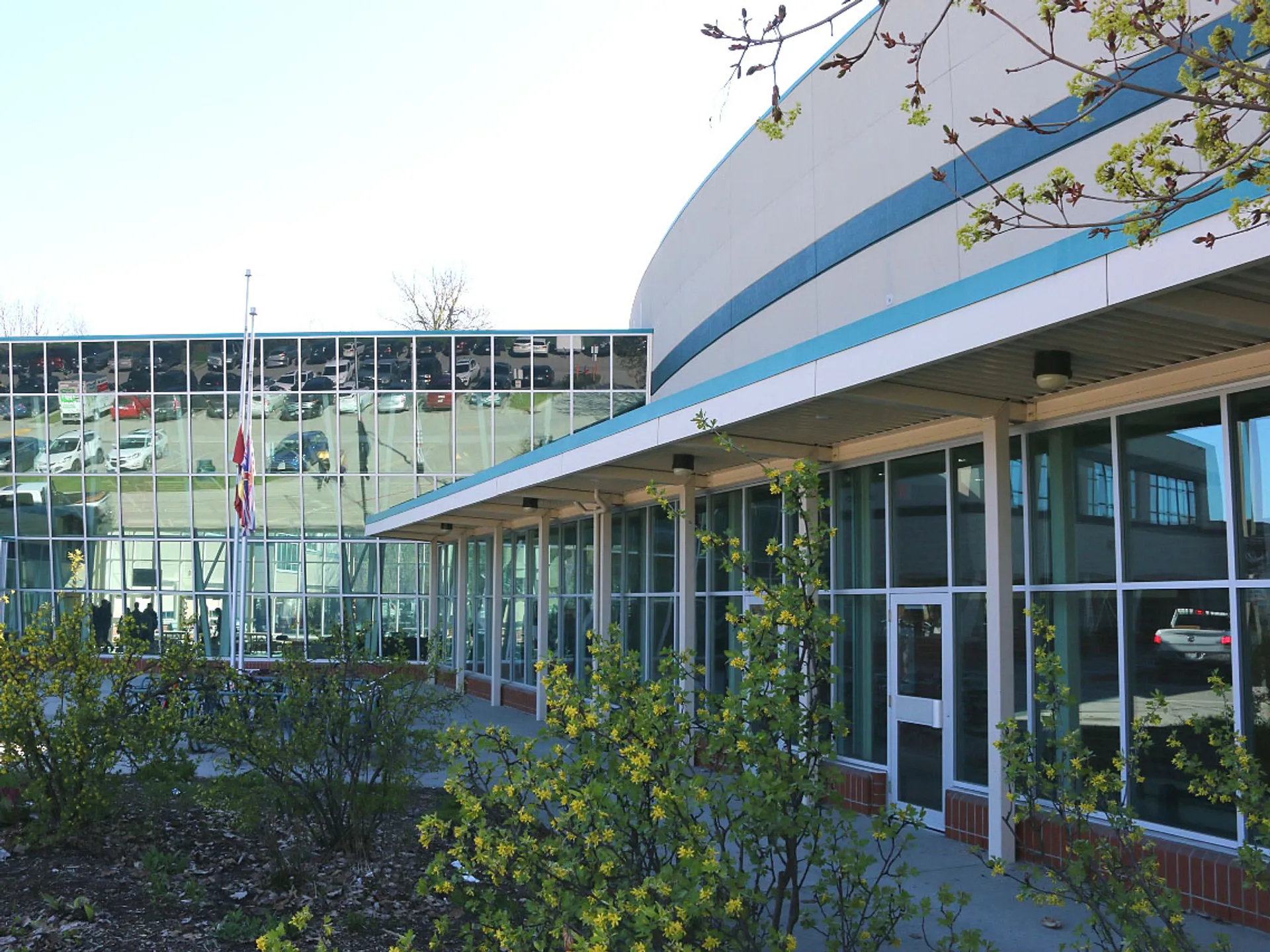 L'edificio moderno della George Elliot Secondary School con facciata in vetro e tetto curvo circondato da aree verdi.