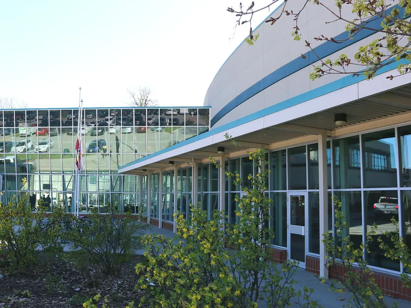 L'edificio moderno della George Elliot Secondary School con facciata in vetro e tetto curvo circondato da aree verdi.