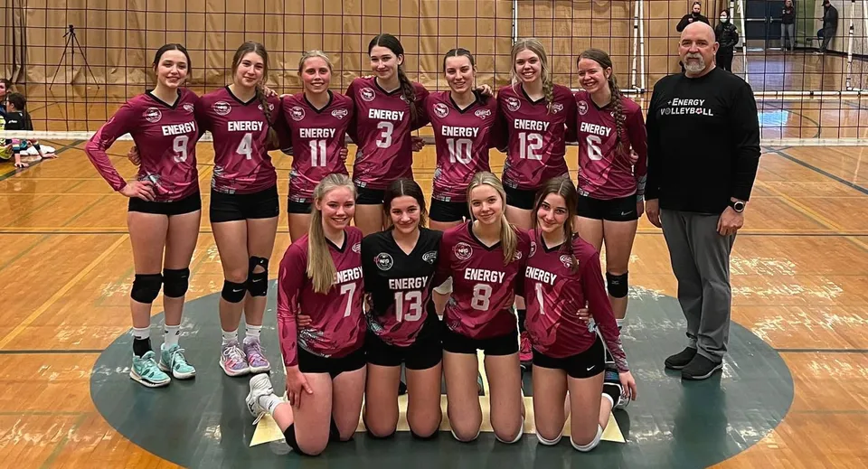Un gruppo di giocatrici di pallavolo della Rutland Senior Secondary School posa insieme al proprio allenatore nella palestra.