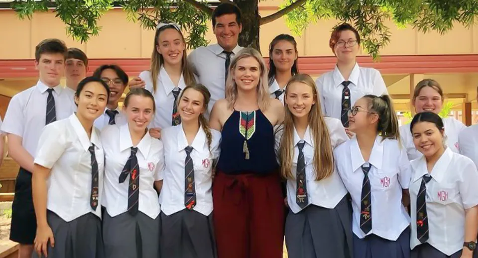 Un gruppo di studenti della Mount Gravatt State High School si trova in un'aula con un albero verde sullo sfondo.