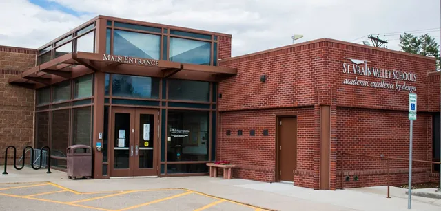 L'edificio in mattoni con l'ingresso principale delle St. Vrain Valley Schools si trova sotto un cielo nuvoloso ed è circondato da un'area pavimentata.