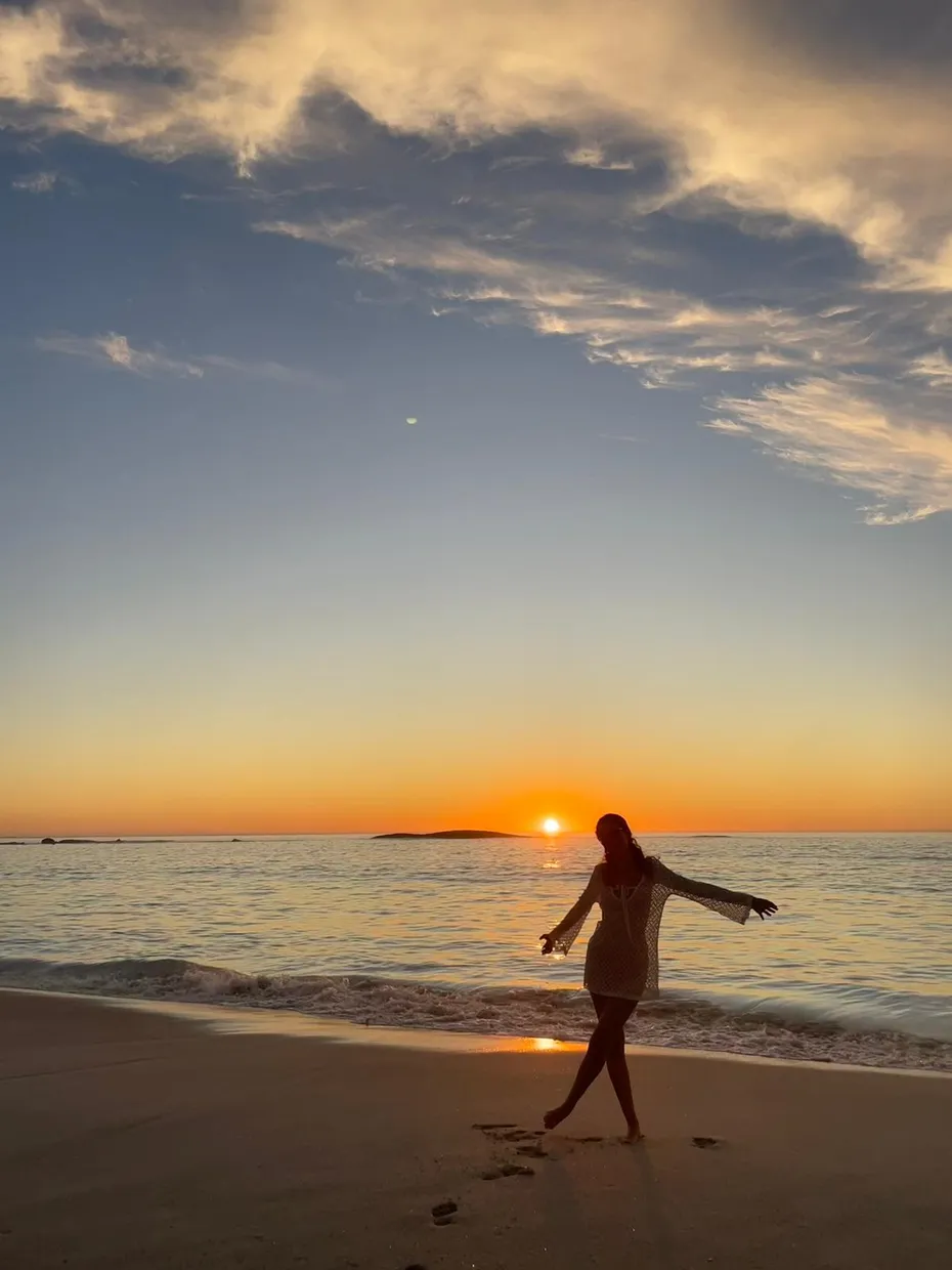Silhouette di una ragazza che cammina sulla spiaggia al tramonto sul mare