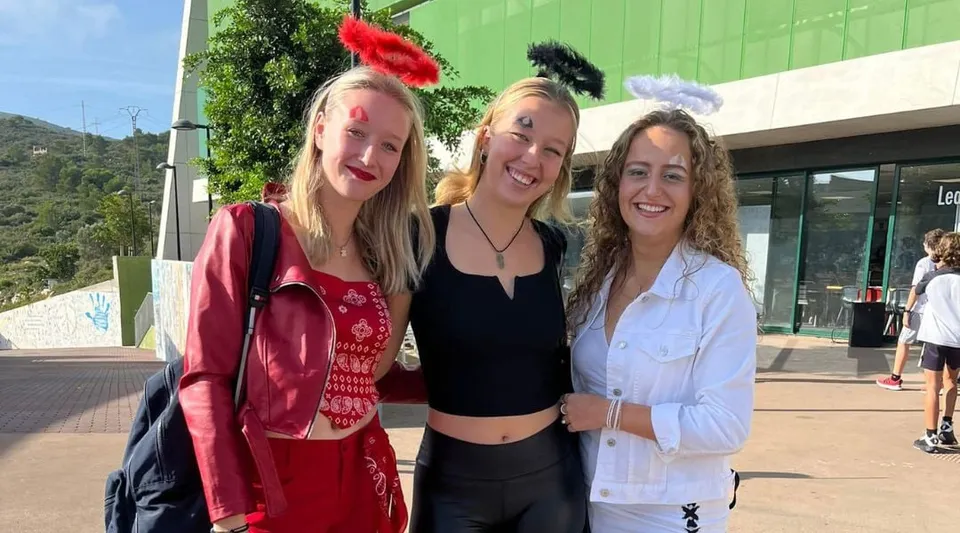 Tre studentesse della Laude Lady Elizabeth School in piedi insieme davanti a un edificio verde.