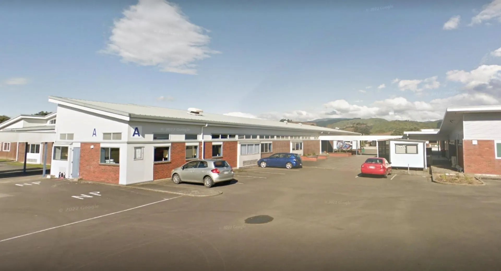 L'edificio scolastico a un piano del Paraparaumu College con parcheggio e paesaggio collinare sullo sfondo.