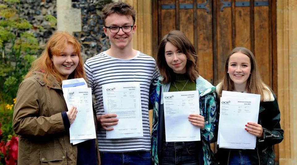 Quattro studenti della Thetford Grammar School sono all'aperto e mostrano con orgoglio i loro certificati.