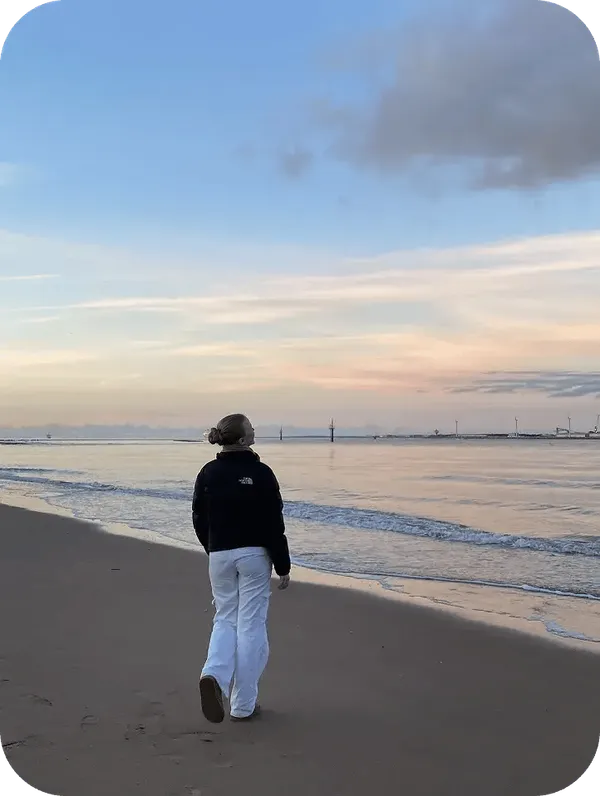 Austauschschülerin geht bei Sonnenuntergang am Strand entlang