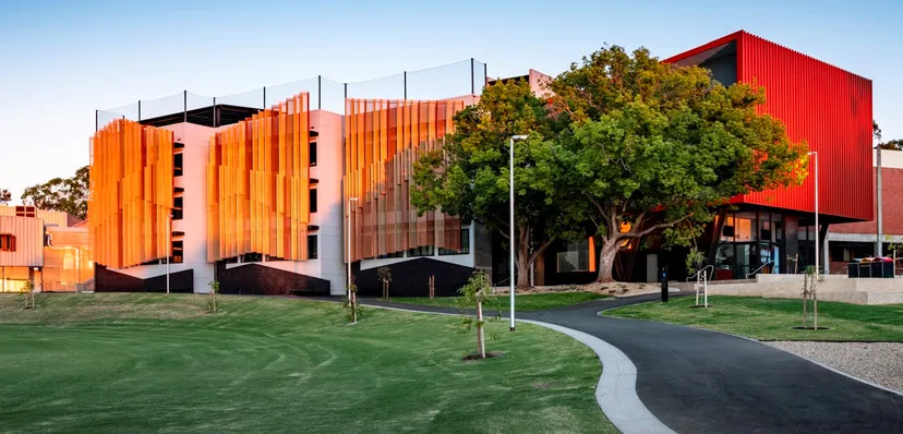 L'edificio moderno della Norwood International High School con facciate rosse e arancioni in un paesaggio verde.