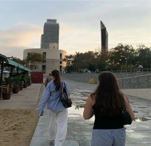 Zwei Mädchen gehen die Strandpromenade einer spanischen Stadt entlang