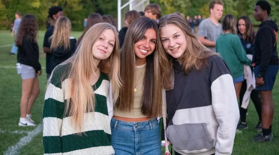 Un gruppo di studentesse dai capelli lunghi ride su un prato nel campus della La Lumiere School.