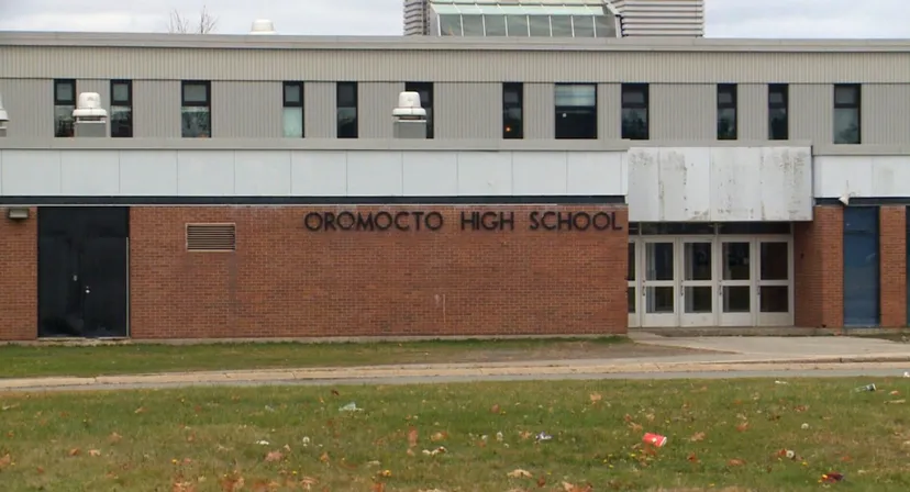 L'edificio in mattoni della Oromocto High School è circondato da un prato con foglie cadute.