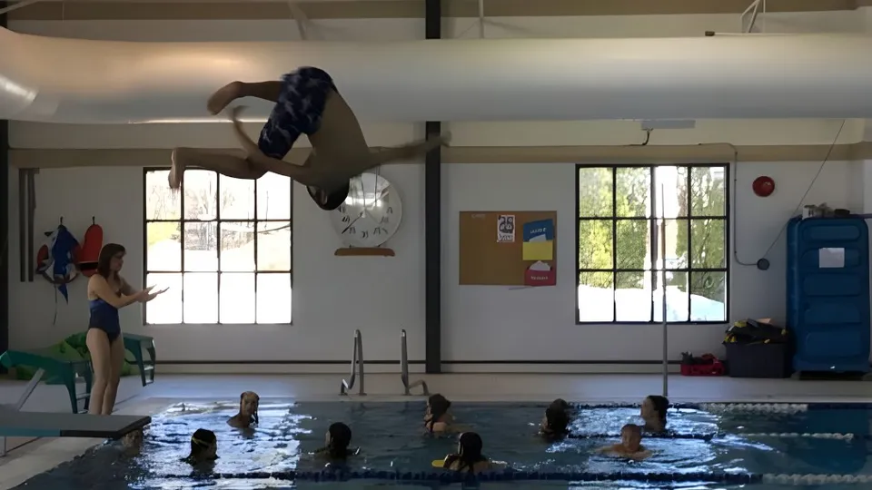 Una persona fa un tuffo nella piscina coperta all'interno del campus della École Sophie Morigeau.