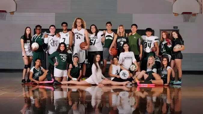 Un grupo de estudiantes posando en la cancha de baloncesto de la Holy Cross Catholic Secondary School con balones de baloncesto y ropa deportiva.