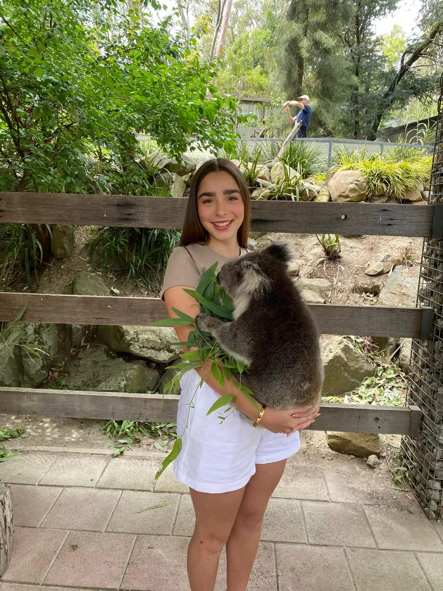 Ragazza sorridente tiene in braccio un koala in un parco faunistico in Australia