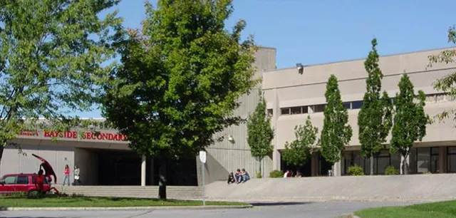 L'edificio moderno a più piani della Bayside Secondary School è circondato da alberi e da un'area verde.