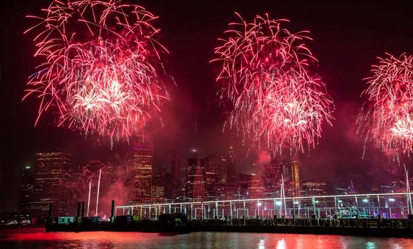 Fuegos artificiales rojos explotando en el cielo nocturno sobre los rascacielos de una ciudad