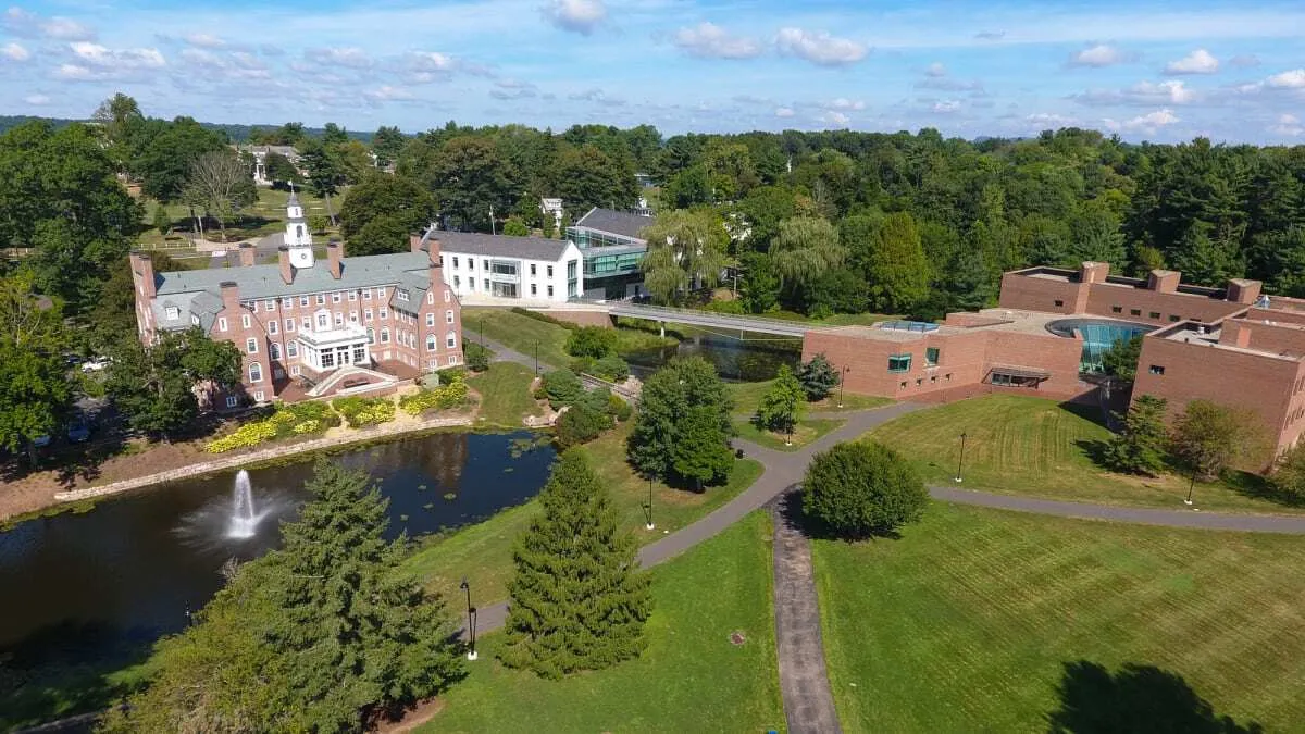 Vista aérea del campus de Choate Rosemary Hall con edificios de ladrillo, un lago con fuente y amplias áreas verdes.