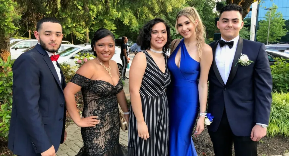 Cinque persone ben vestite posano insieme davanti a uno sfondo verde nel campus del Fraser Coast Anglican College.