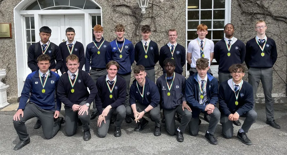 Un gruppo di studenti della Dundalk Grammar School sta davanti a un edificio con facciata in pietra e finestre ad arco.