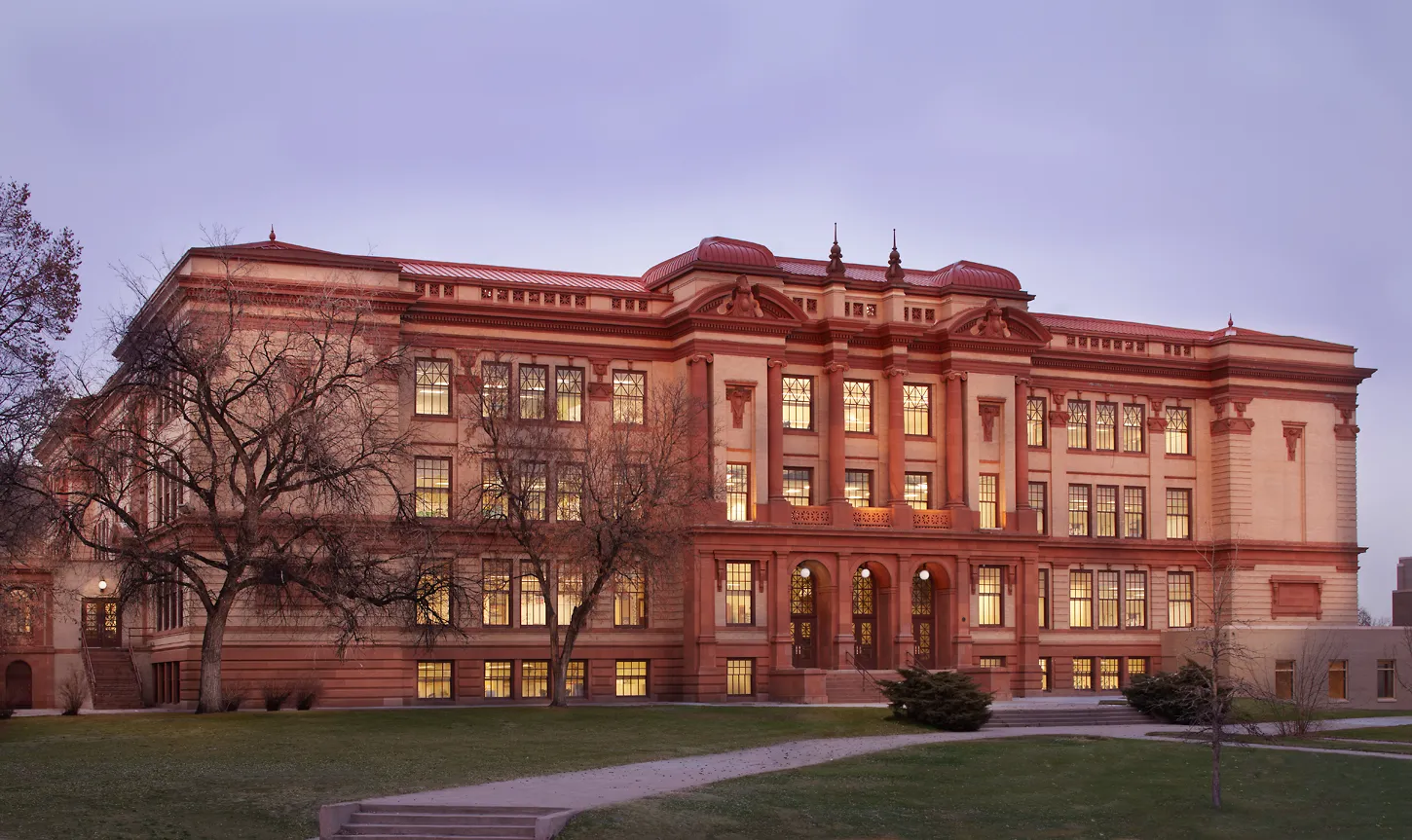 El edificio histórico del Denver Public School District con ventanas iluminadas al atardecer.