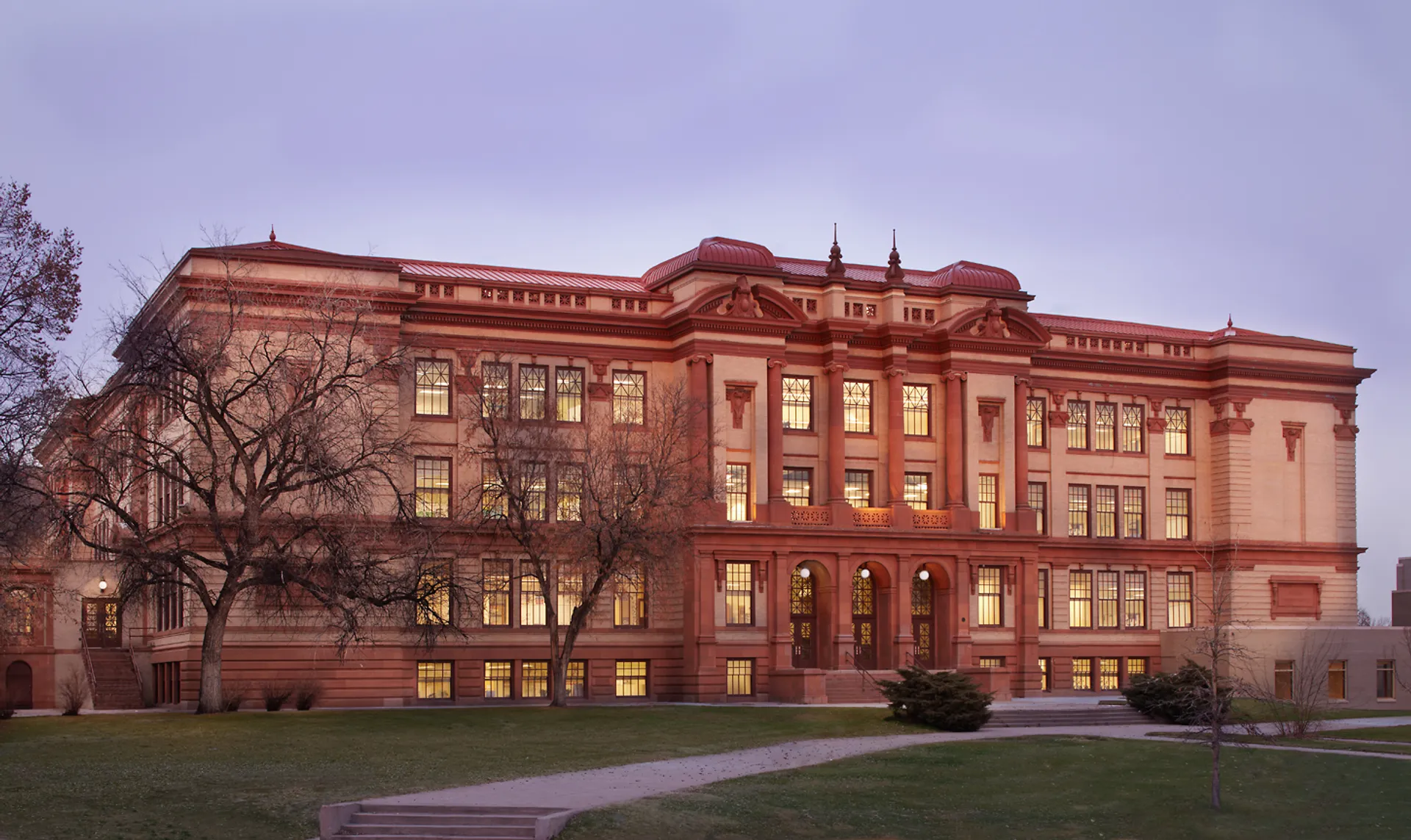 L'edificio storico del Denver Public School District con finestre illuminate al tramonto.
