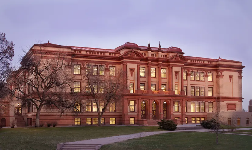 L'edificio storico del Denver Public School District con finestre illuminate al tramonto.