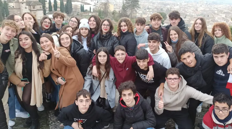 Un grande gruppo di studenti della Salesianas si trova all'aperto in città e posa per una foto di gruppo.