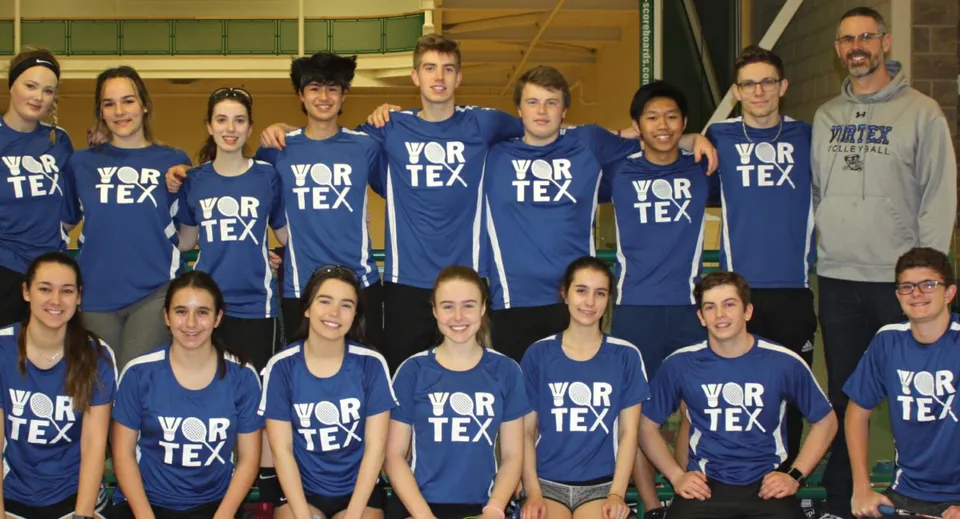Un gruppo di studenti e studentesse della Tecumseh Vista Academy si trova insieme in un centro sportivo indossando magliette blu con la scritta VORTEX.