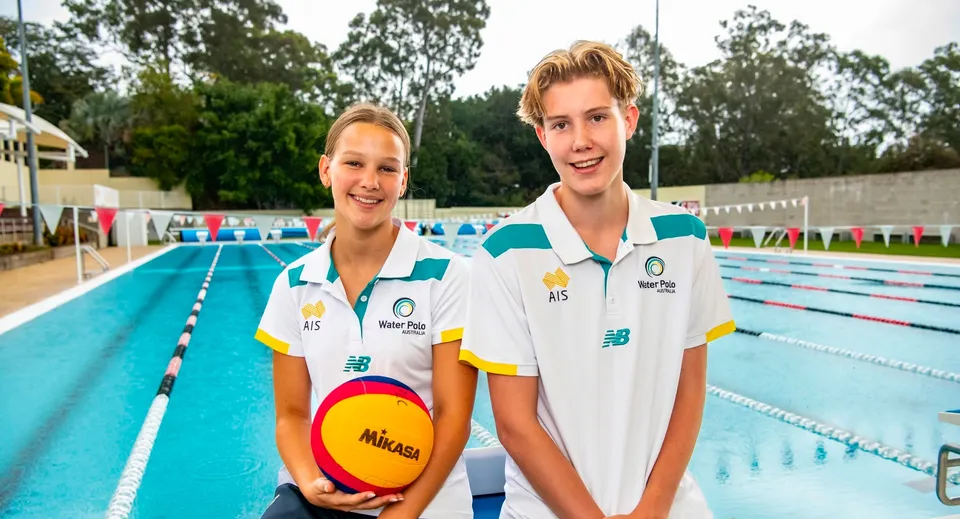 Due giovani atleti in abbigliamento sportivo accanto alla piscina del campus del St. Peters Lutheran College tengono un pallone da pallavolo.