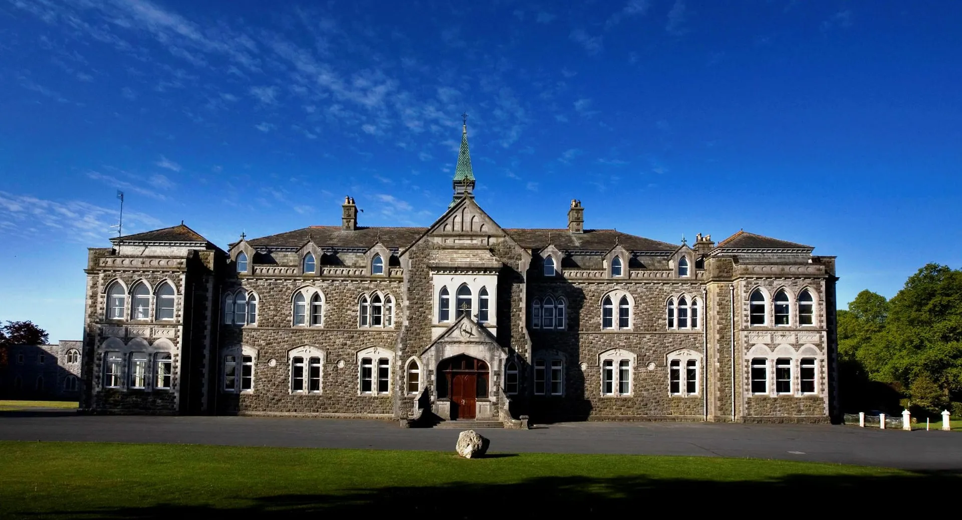 L'edificio principale storico del Cistercian College è circondato da un prato verde e si trova sotto un cielo blu.
